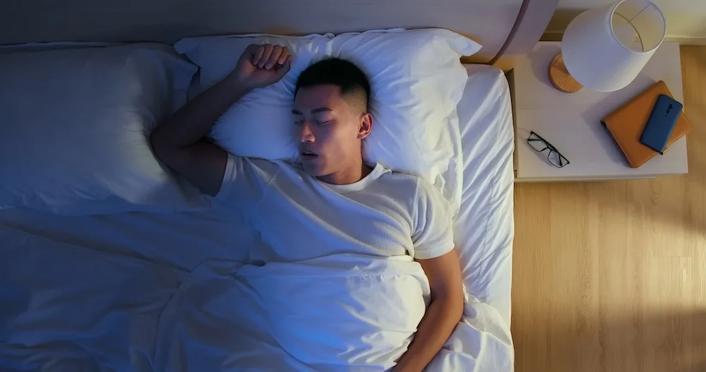 仰向けで口を開けて眠る男性(いびきが出やすい寝方)